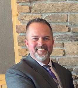Man in suit smiling in from of brick